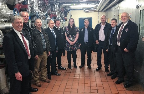 A photograph of group from the Association of University Engineers in the engine and boiler room of Dundee University's CHP plant