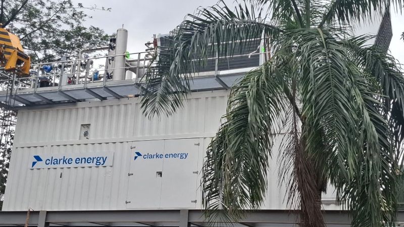 Centrale de trigénération située dans le bâtiment de Dream Cosmetics, avec le logo de Clarke Energy et des arbres à l'extérieur