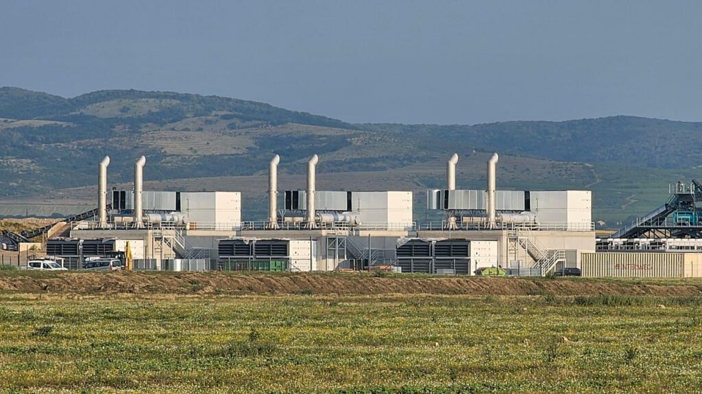Image shows Navios Investments Racari plant in Romania with hills in the background and field in front